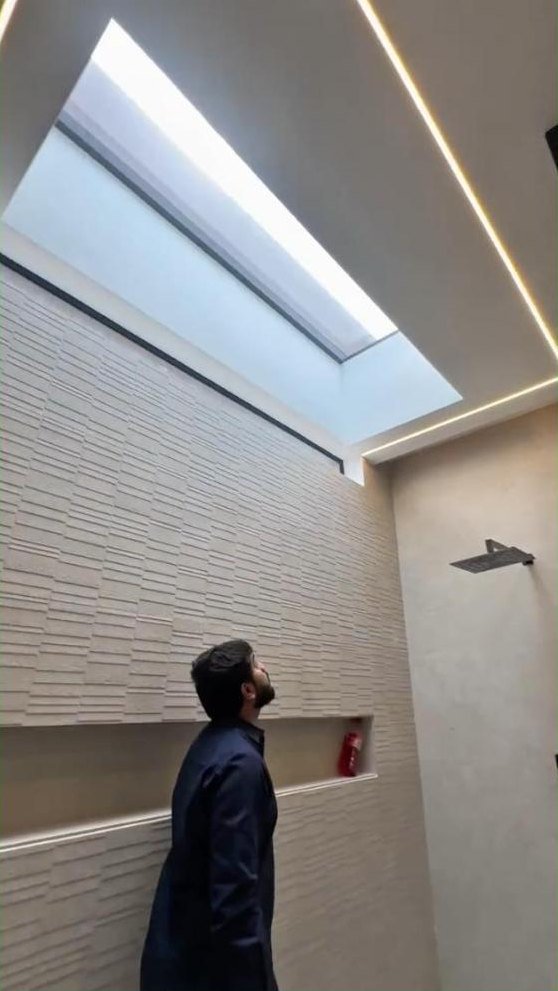 Bathroom with a skylight, textured wall tiles and a lit niche